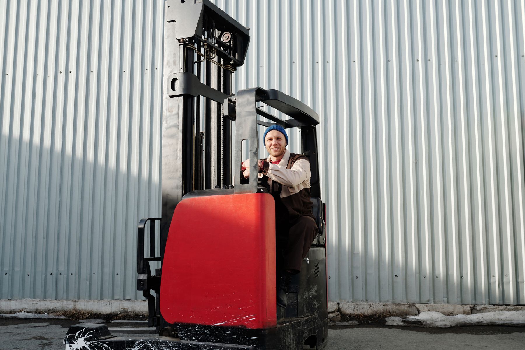Warehouse worker operating a forklift beside an industrial building