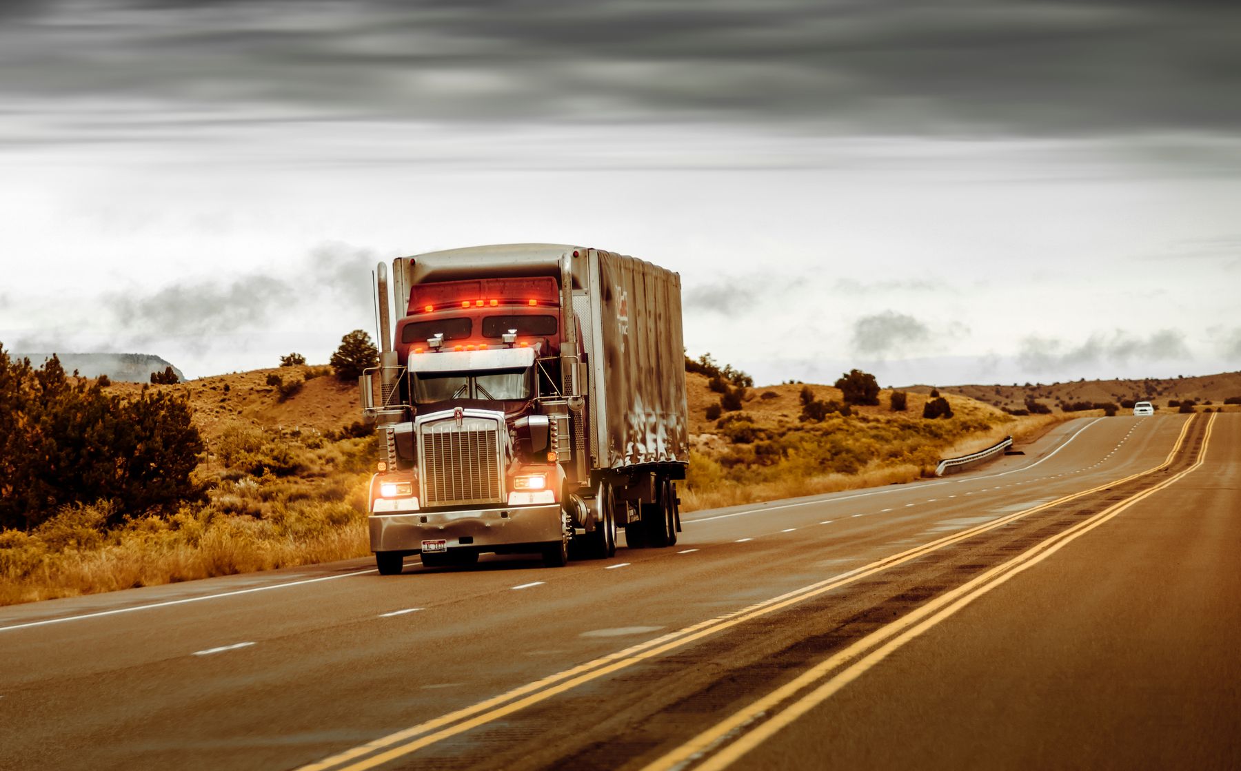 American semi truck carrying a box trailer on an open highway